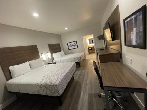 a hotel room with two beds and a desk at Palace Inn Blue - Garth Rd in Baytown