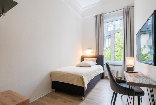 a bedroom with a bed and a desk and a window at Hotel Aurora in Wiesbaden