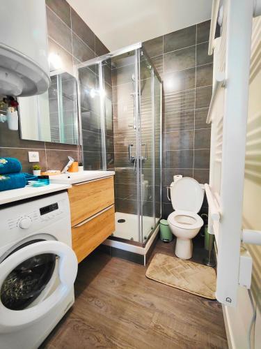 a bathroom with a shower toilet and a washing machine at T3 neuf L'INDUSTRIEL in Riom