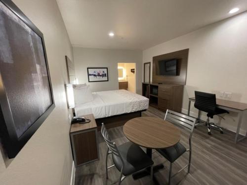 a hotel room with a bed and a table and chairs at Palace Inn Blue - Garth Rd in Baytown