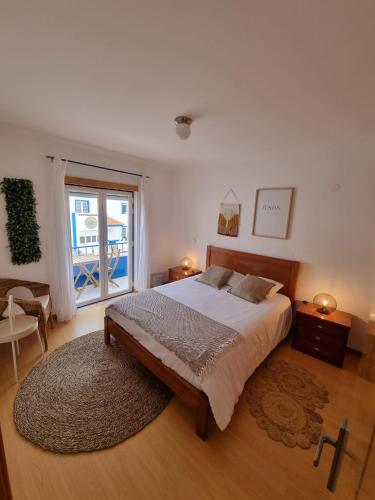 a bedroom with a large bed and a large window at Be Baleal Surfhouse in Baleal