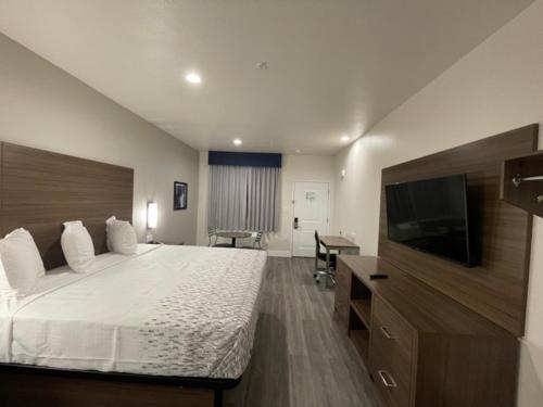 a hotel room with a bed and a flat screen tv at Palace Inn Blue - Garth Rd in Baytown