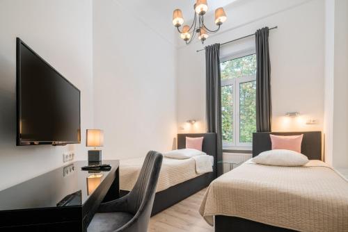 ein Hotelzimmer mit 2 Betten und einem Flachbild-TV in der Unterkunft Hotel Aurora in Wiesbaden