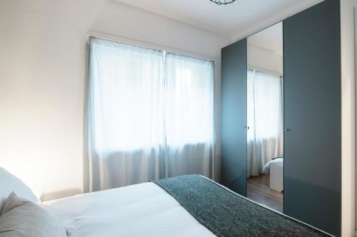 a bedroom with a white bed and a mirror at Lido Apartments by Quokka 360 - 5 min from the centre and the Lugano Lido in Lugano