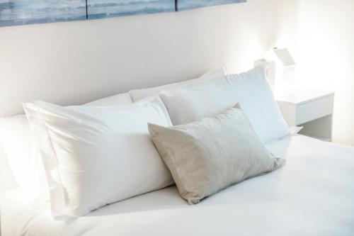 a pile of white pillows sitting on a bed at Lido Apartments by Quokka 360 - 5 min from the centre and the Lugano Lido in Lugano