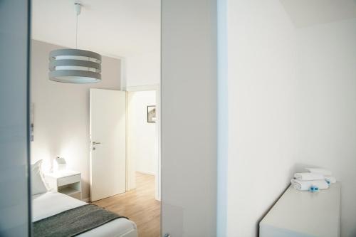 a white room with a bed and a mirror at Lido Apartments by Quokka 360 - 5 min from the centre and the Lugano Lido in Lugano