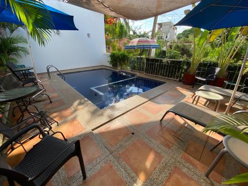 a patio with a swimming pool with chairs and umbrellas at Chacala Arrecifes 1 para 2 con Aire Acondicionado a solo 50 mts de la Playa ARF1 in Chacala
