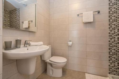 Un baño blanco con inodoro y lavabo. en Begonia, en Orihuela Costa