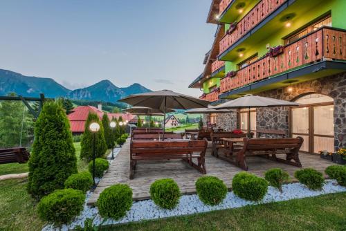 a patio with benches and umbrellas in front of a building at Penzión Šafrán in Ždiar