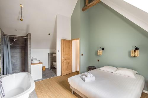 a bedroom with a white bed and a bath tub at LA PILOTINE - maison 2 chambres in Saint-Coulomb