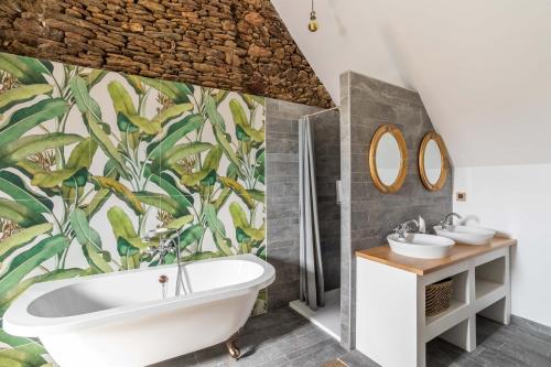 a bathroom with a white tub and a tropical wallpaper at LA PILOTINE - maison 2 chambres in Saint-Coulomb