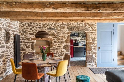 une salle à manger avec un mur en pierre, une table et des chaises dans l'établissement LA PILOTINE - maison 2 chambres, à Saint-Coulomb