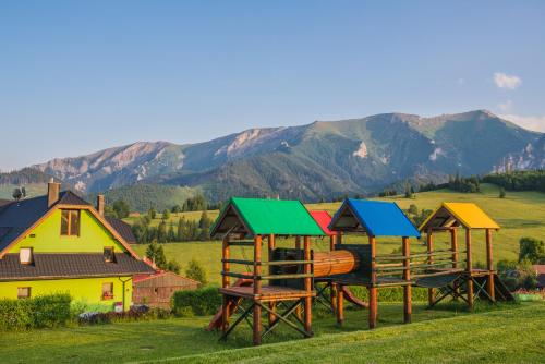 a group of wooden play structures in a field with mountains at Penzión Šafrán in Ždiar
