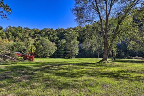 a red truck parked in a field with a tree at Silver Creek Cabin with Hiking Less Than 1 Mi to Town! in Beattyville