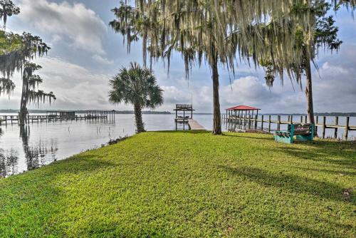 a grassy area with trees and a dock in the water at Pirate Cove Home in Welaka Dock and River Access! in Welaka