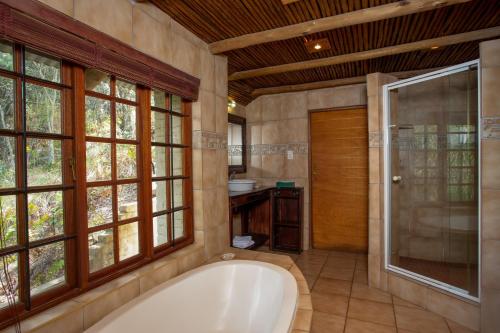 uma casa de banho com uma banheira, um chuveiro e janelas. em Whispering Pines Country Estate em Magaliesburg