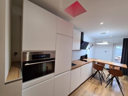 a kitchen with white cabinets and a wooden table at Tedy style in De Haan