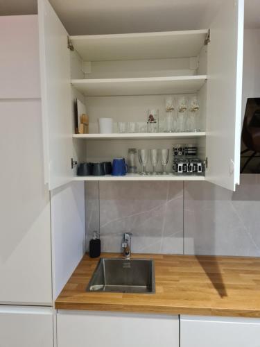 a kitchen with white cabinets and a sink at Tedy style in De Haan