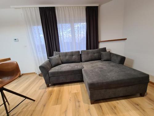 a living room with a gray couch in front of some windows at Tedy style in De Haan