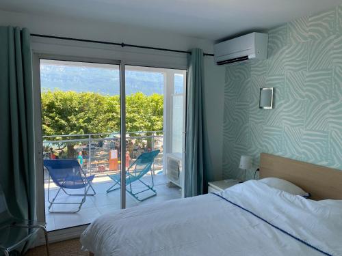 a bedroom with a bed and a balcony with chairs at Les Suites du Port in Le Bourget-du-Lac