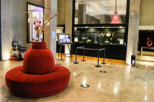 a lobby with a red ottoman in front of a store at Savoy Hotel in Buenos Aires