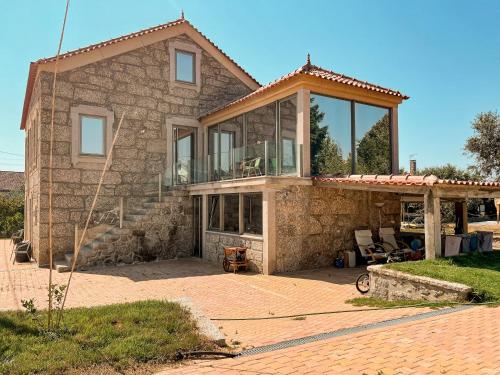 a stone house with a large glass window at DIGNUS HOUSE in Folhadosa