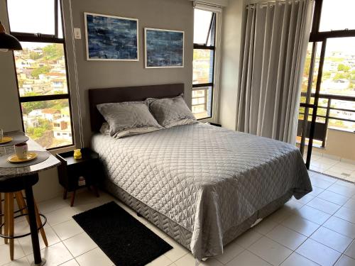 a bedroom with a bed and some windows at Apartamento Studio - Novíssimo e Aconchegante em Caxambu MG in Caxambu