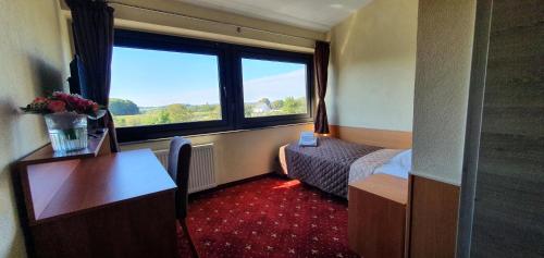 a hotel room with a bed and a desk and a window at Hotel Poock in Haan