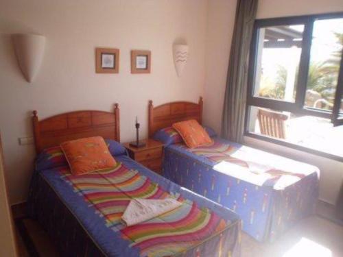 two twin beds in a room with a window at Villa Carabela 83 in Playa Blanca