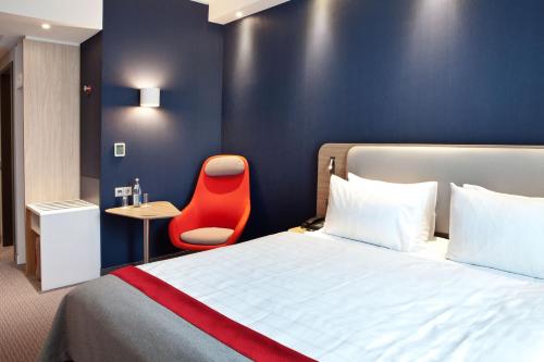 Pokój hotelowy z łóżkiem i czerwonym krzesłem w obiekcie Holiday Inn Express Oberhausen, an IHG Hotel w mieście Oberhausen