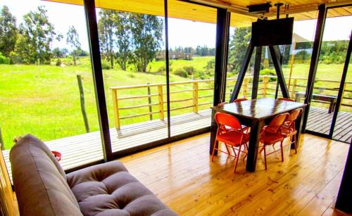 a living room with a table and chairs and a couch at Lodge KARKÚ in Pichilemu