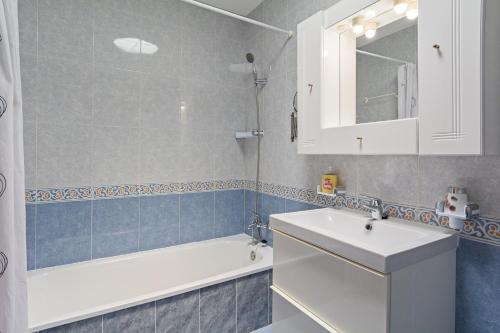 ein Badezimmer mit einem weißen Waschbecken, einer Badewanne und einem Spiegel in der Unterkunft Villa Mariposa in Playa Blanca