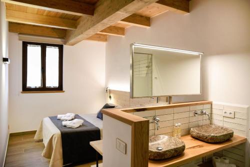 a bathroom with a sink and a bed and a mirror at EL SERRADELL AGROTURISME in Sant Joan de les Abadesses