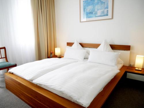 a bedroom with a large bed with white sheets and pillows at Pension Helma in Bad Neuenahr-Ahrweiler