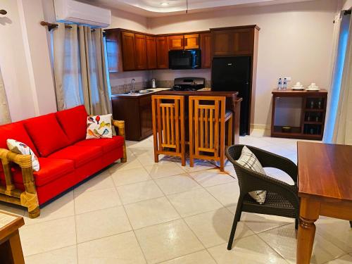 a living room with a red couch and a kitchen at La Isla Resort in Caye Caulker