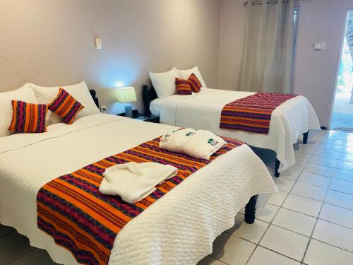 two beds with towels on them in a room at La Isla Resort in Caye Caulker