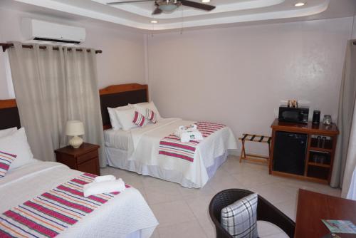 a hotel room with two beds and a tv at La Isla Resort in Caye Caulker