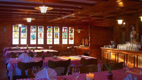 ein Restaurant mit Tischen, Stühlen und Buntglasfenstern in der Unterkunft Gasthaus Tübli Gersau in Gersau