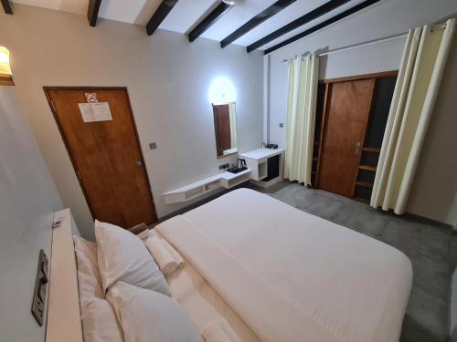 ein Schlafzimmer mit einem großen weißen Bett in einem Zimmer in der Unterkunft Dhooni Finolhu Guesthouse in Maalhos
