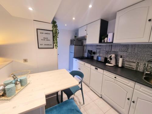 a kitchen with white cabinets and a wooden table at La Tiny proche lac et forêt in Sillé-le-Guillaume