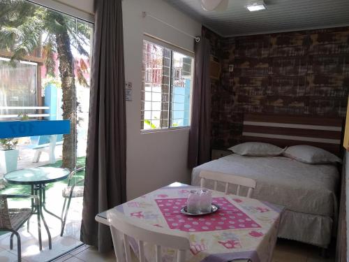 Un pequeño dormitorio con una cama y una mesa con sidra de mesa en Pousada Bella Praia, en Torres