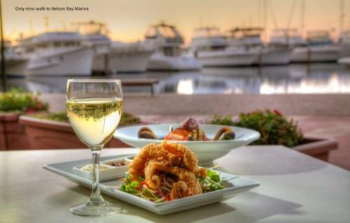 a plate of food and a glass of white wine at Casablanca In Landmark Resort in Nelson Bay