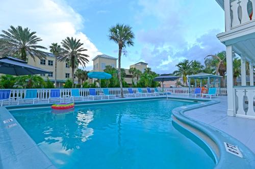 a pool at a resort with blue chairs and palm trees at The Islander Inn in Vero Beach