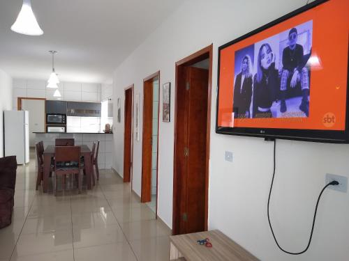 une télévision accrochée au mur dans le salon dans l'établissement Casa Nova com Piscina 3 quartos, à Guaratuba