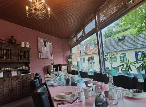 a dining room with a long table and a large window at Hotel B&B LeLa in Valkenburg