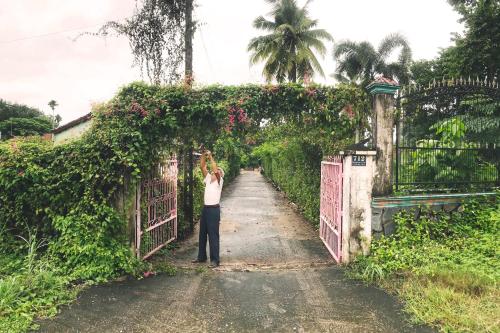 a woman standing in front of a gate at Vườn Nhà Ngoại Garden Homestay in Cu Chi