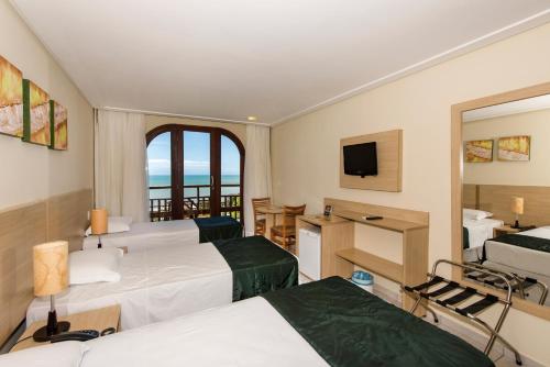 a hotel room with two beds and a television at Rede Andrade Comfort in Natal