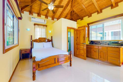 a bedroom with a wooden bed and a kitchen at FLA at Hummingbird Estate Gold Standard Certified in Dangriga