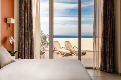 a bedroom with a bed and a view of the beach at Mayflower Hotel Malta in St Paul's Bay