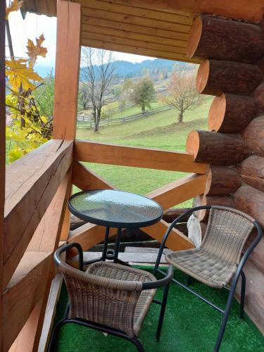 uma mesa e duas cadeiras num alpendre com uma janela em Маєток У Ґазди em Synevyrsʼka Polyana